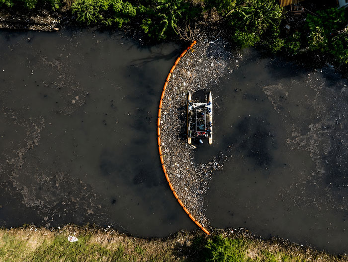 Floating trash boom containing plastic and floating debris in water